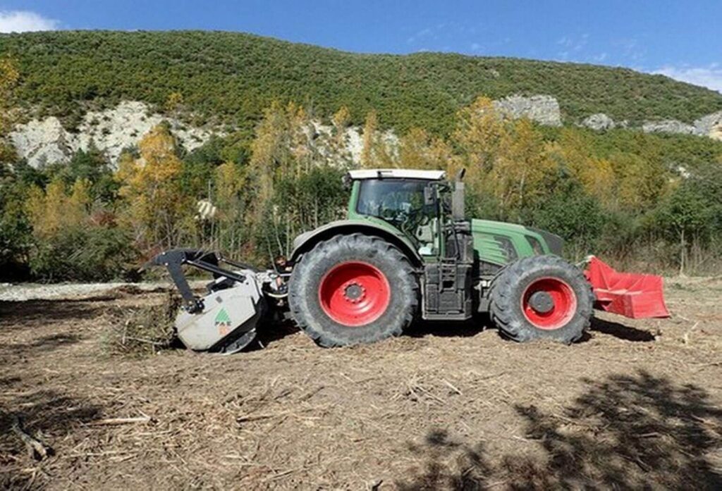 Photo d'un tracteur vert équipé d'un broyeur forestier en train de broyer la végétation d'un îlot dans la Méouge